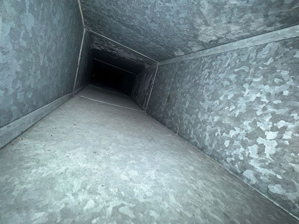 Square metal duct or tunnel interior receding into darkness, viewed from one end