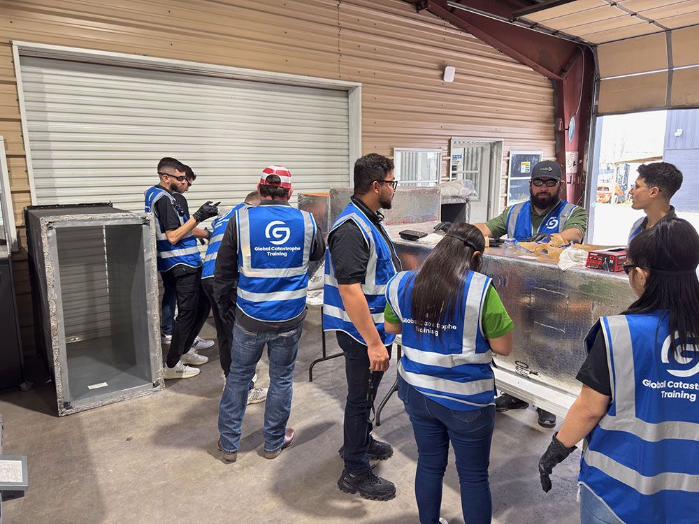 Workers in blue safety vests inspect a large industrial unit in a warehouse loading area.