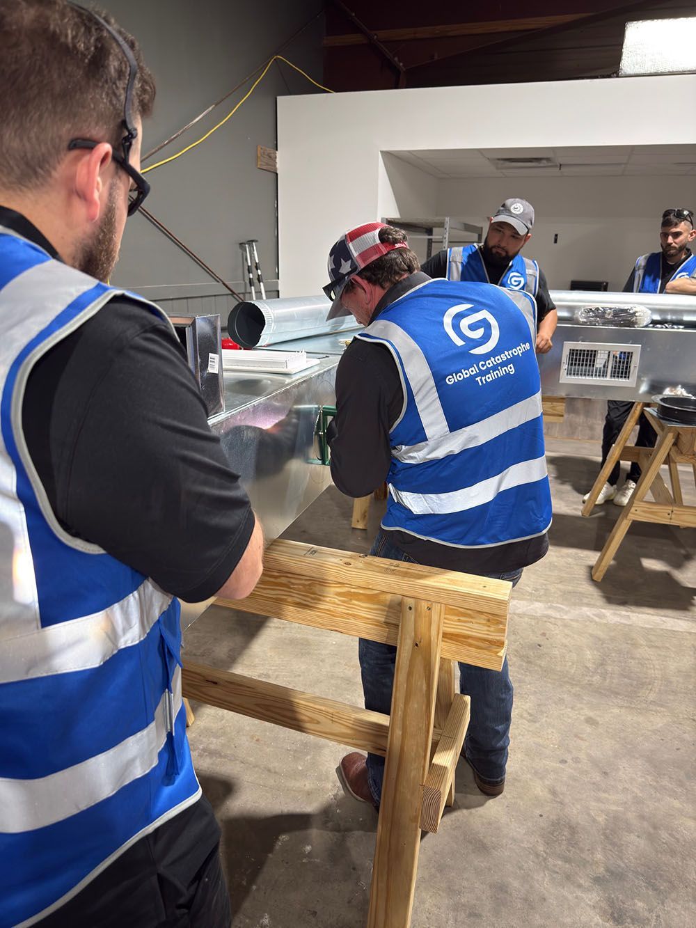 People in blue safety vests working around a car in a workshop