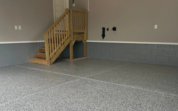 A garage with a staircase leading up to a deck.