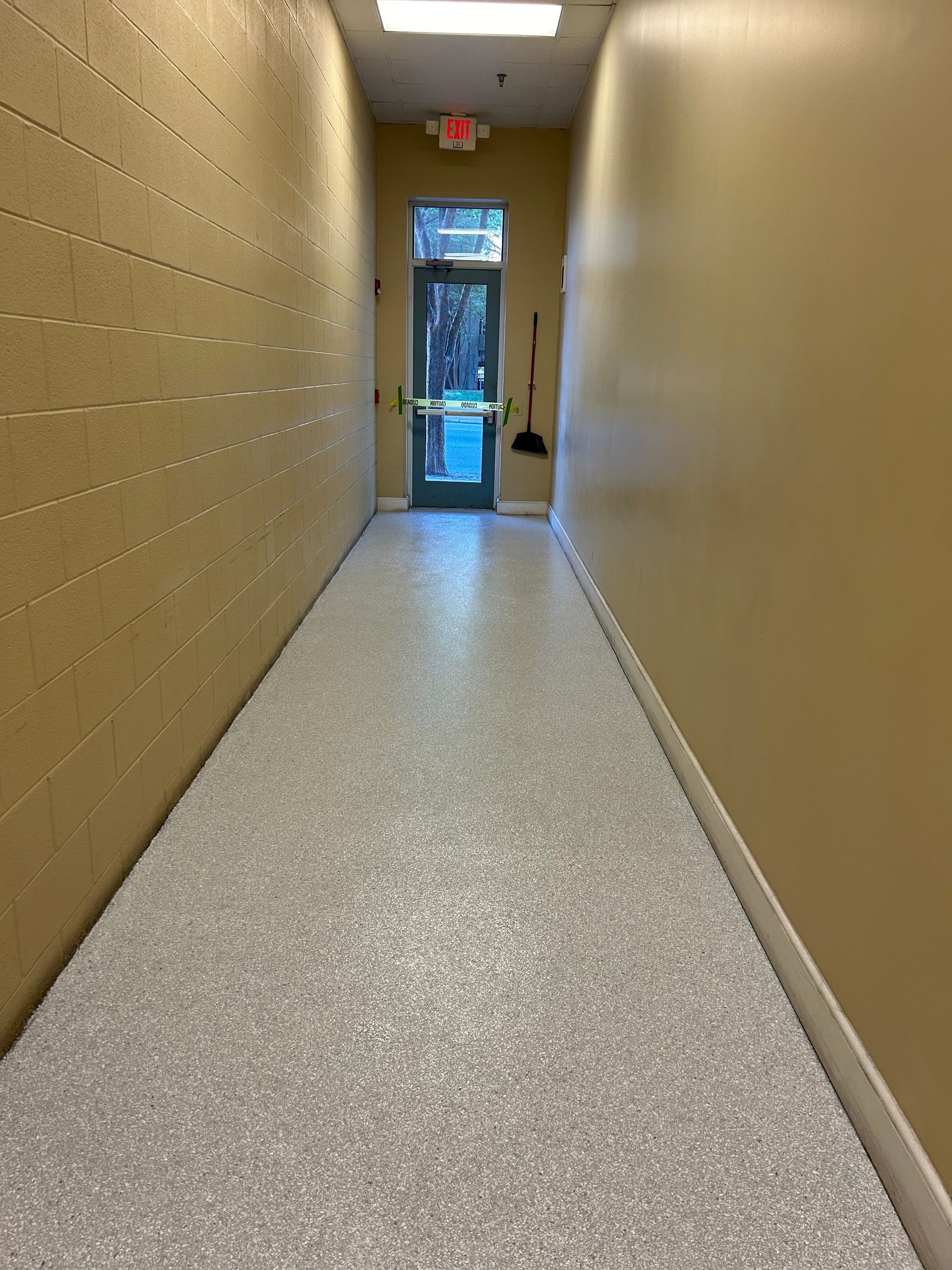 A long hallway with a concrete floor and a door.