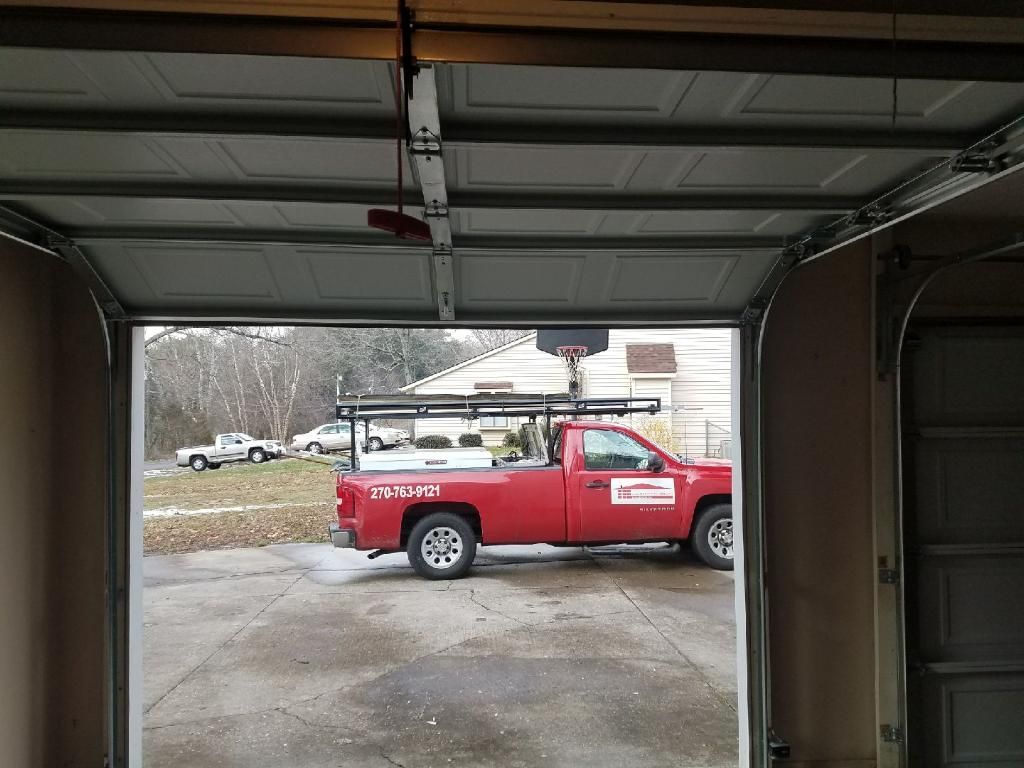 Red utility truck parked in a driveway, viewed from inside an open garage.