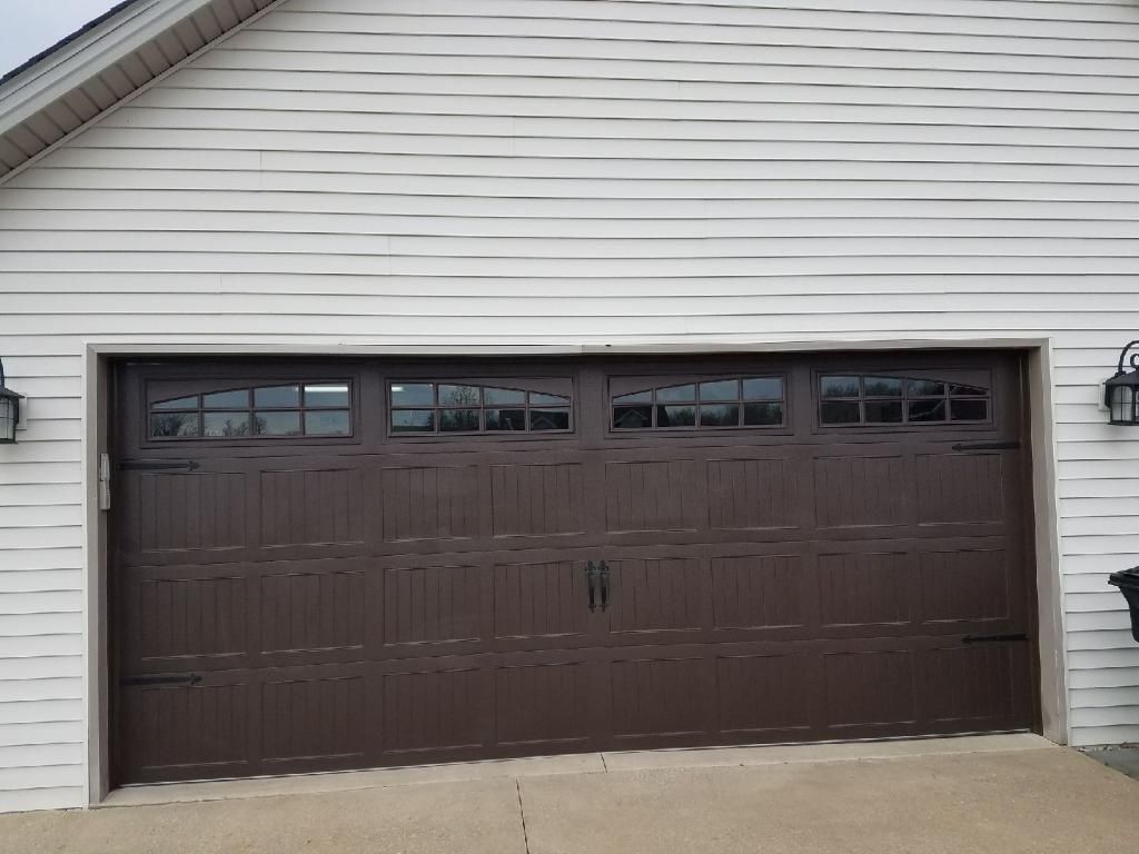 Brown double garage door on a beige house exterior