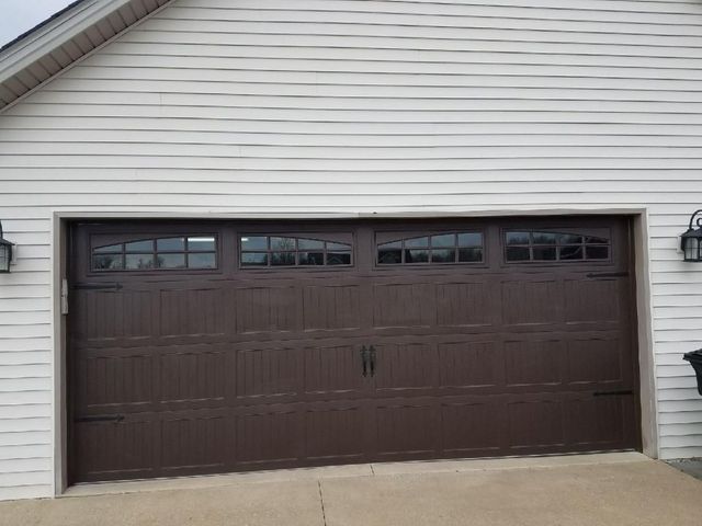 Brown double garage door on a beige house exterior