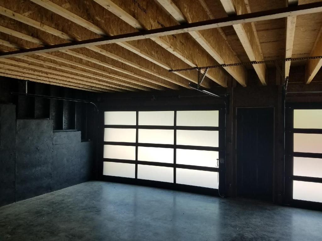 Empty unfinished room with exposed wooden ceiling, black walls, and frosted window panels.