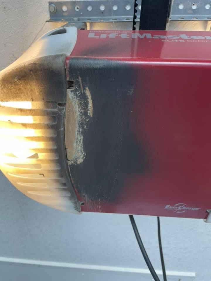 Close-up of a red and black wall-mounted heater with glowing orange vents and peeling paint.