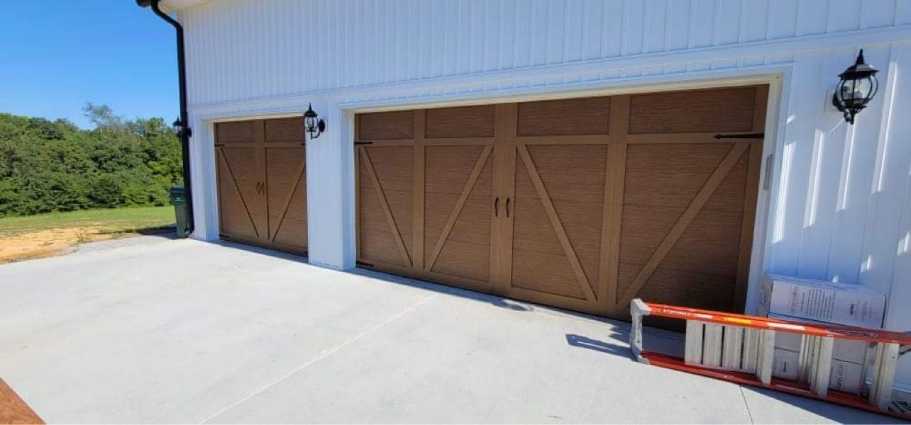 White garage with two wooden doors, side windows, and a concrete driveway in bright sunlight
