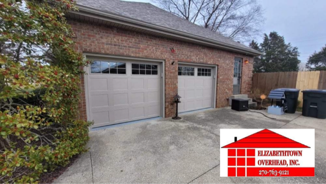 Brick house with two garage doors and a driveway, with trash bins beside the garage