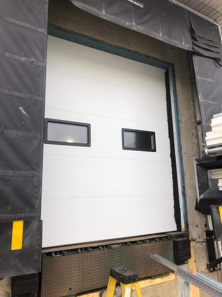 White roll-up garage door with two small windows at a loading dock.