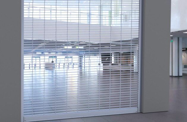 Empty modern lobby seen through white blinds, with a bright open space and polished floor.