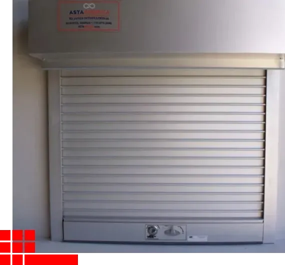 Closed silver metal rolling shutter on a wall with a small control panel below it.