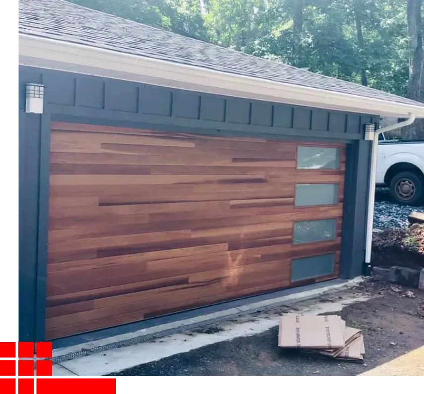 Wood-paneled garage door with frosted windows on a dark blue house exterior, under construction