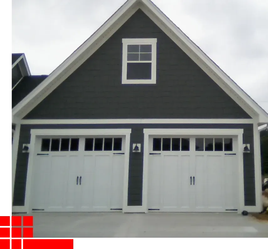 Gray two-car garage with a peaked roof and white trim on a house exterior