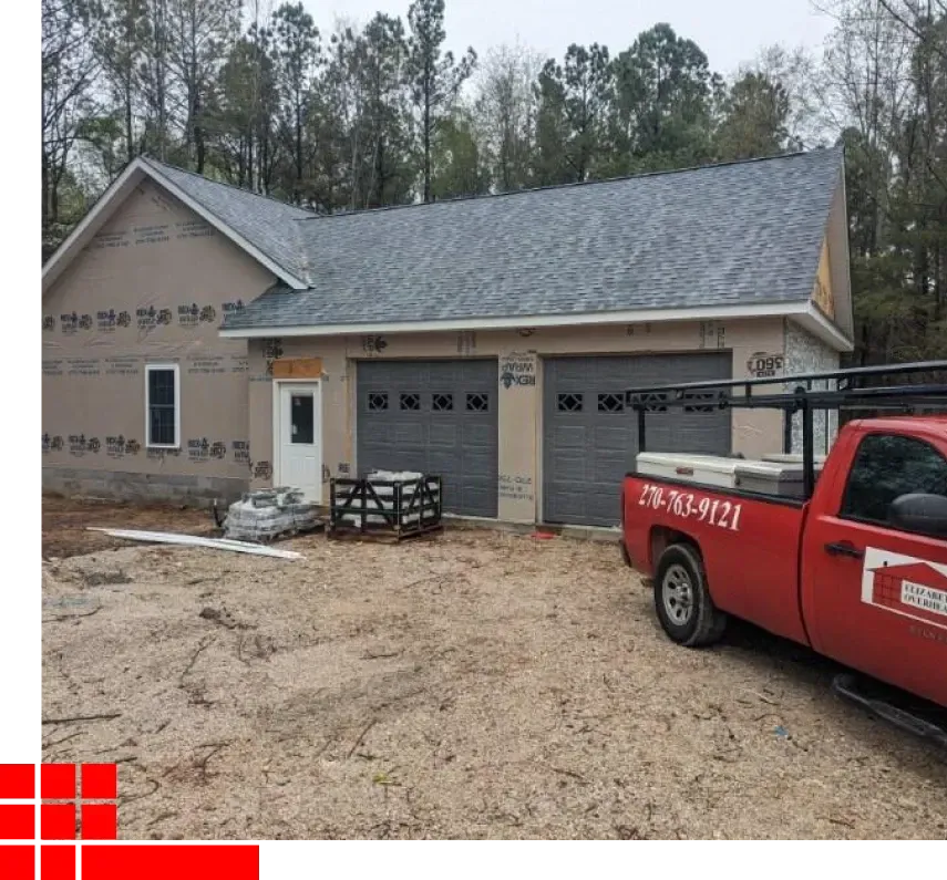 New house exterior under construction with gray siding and a red utility truck in front