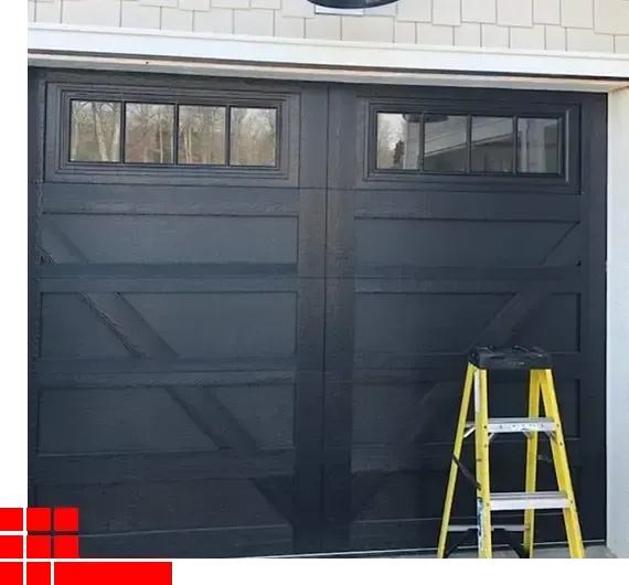 Dark garage door with small windows and a yellow ladder in front of it