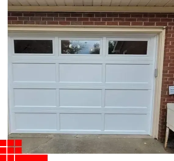 White garage door with three windows, set in a red brick wall over a concrete driveway