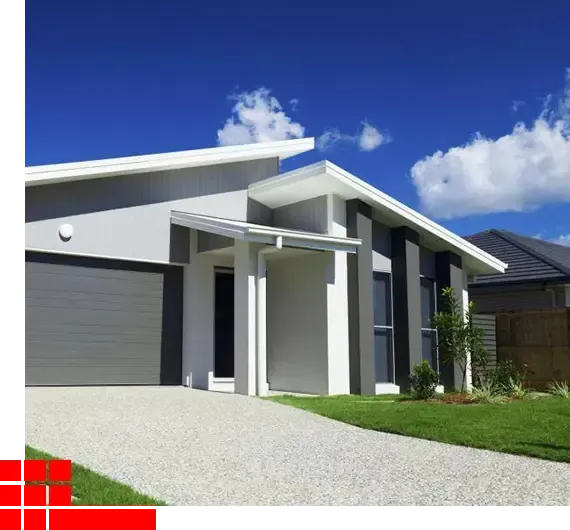 Modern white house with gray garage door, gravel driveway, and blue sky with clouds