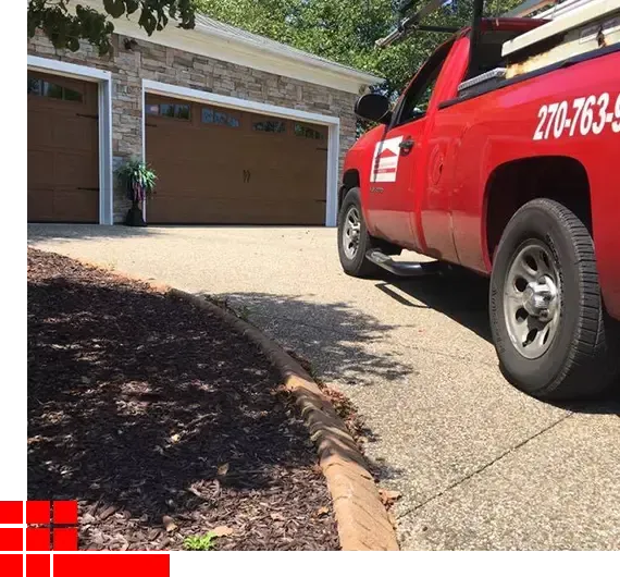 Red service truck parked in a driveway beside a two-car garage on a sunny day