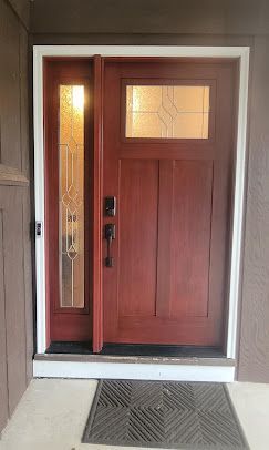 Red front door with sidelights and frosted glass panel, viewed from a covered entryway.