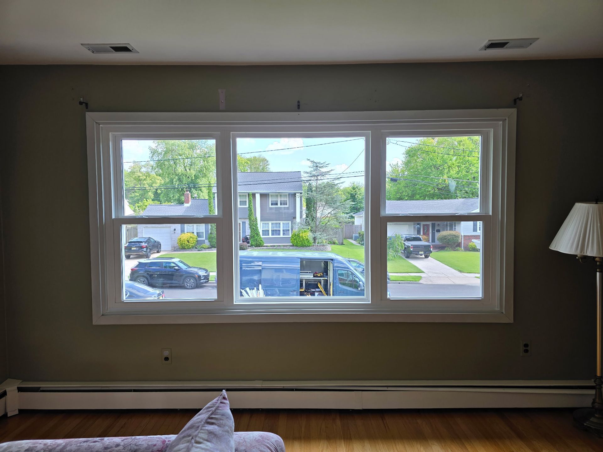 Living room with large window overlooking a suburban street and parked cars