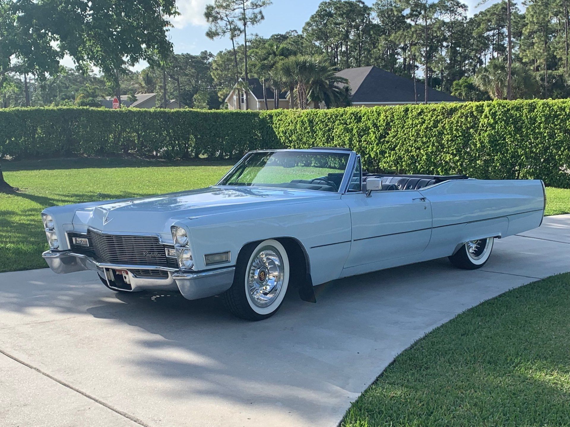 A light blue cadillac convertible is parked on a driveway.