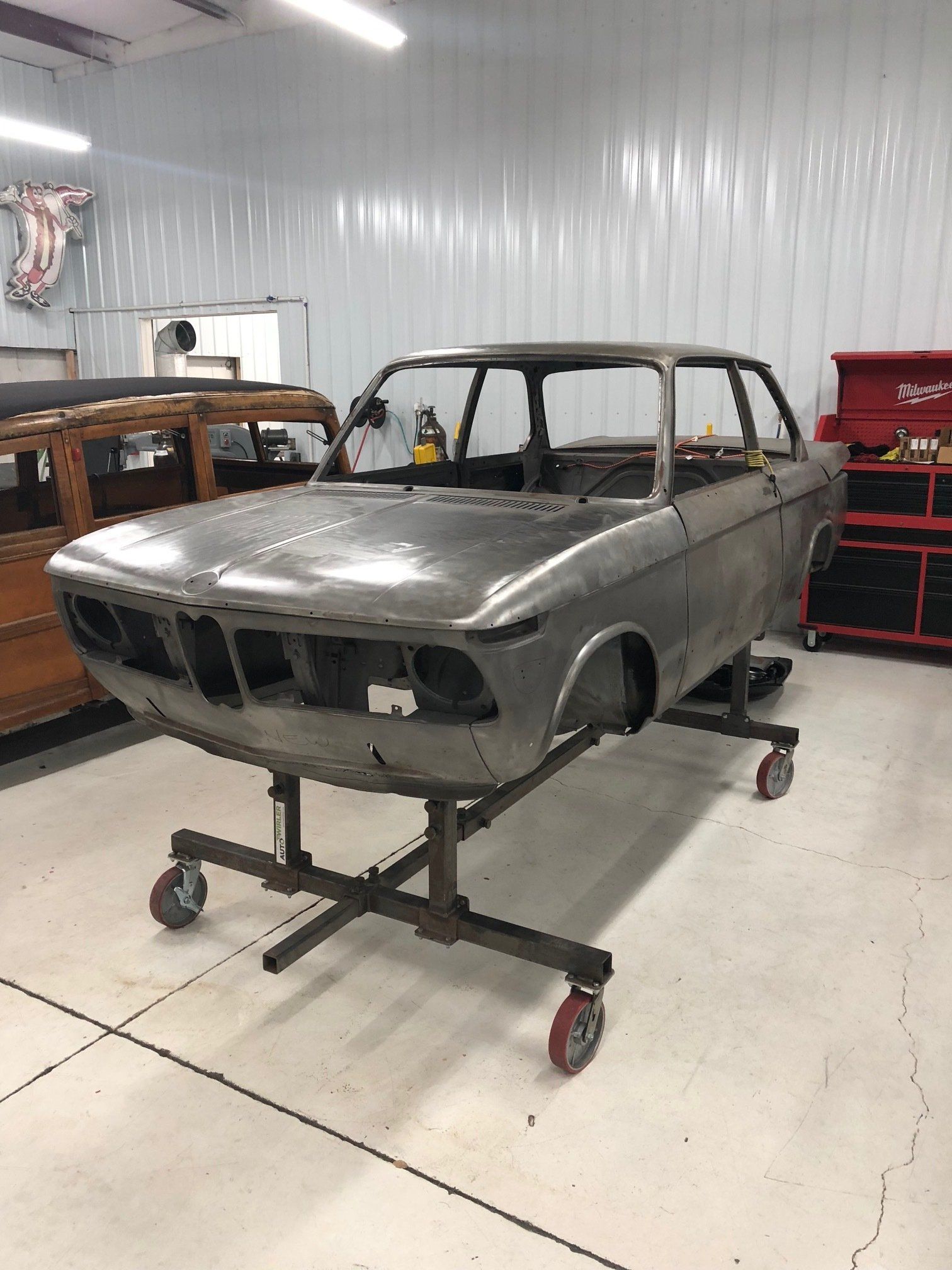 A car body is sitting on a stand in a garage.