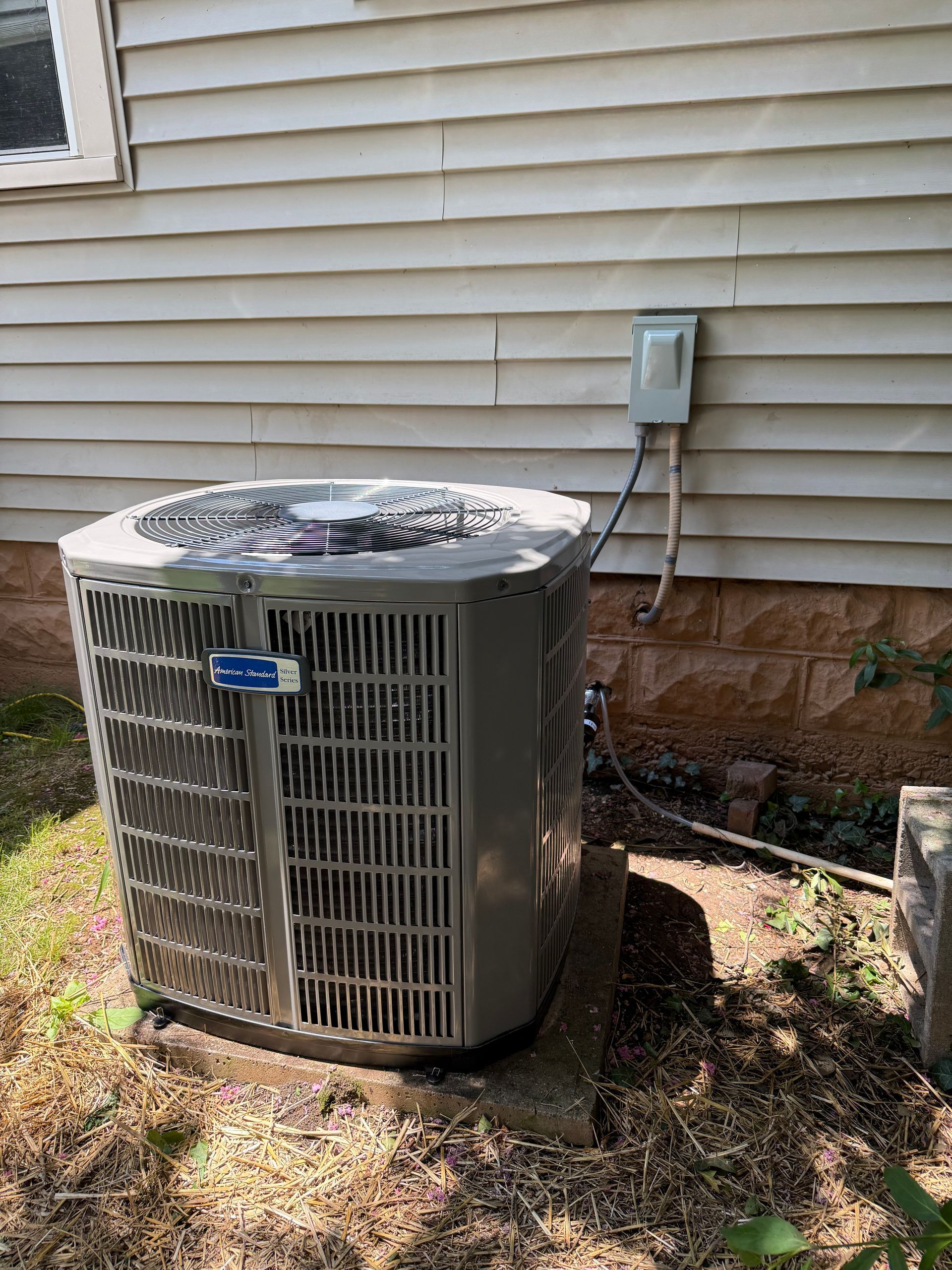 Air conditioning unit outside a house with beige siding.