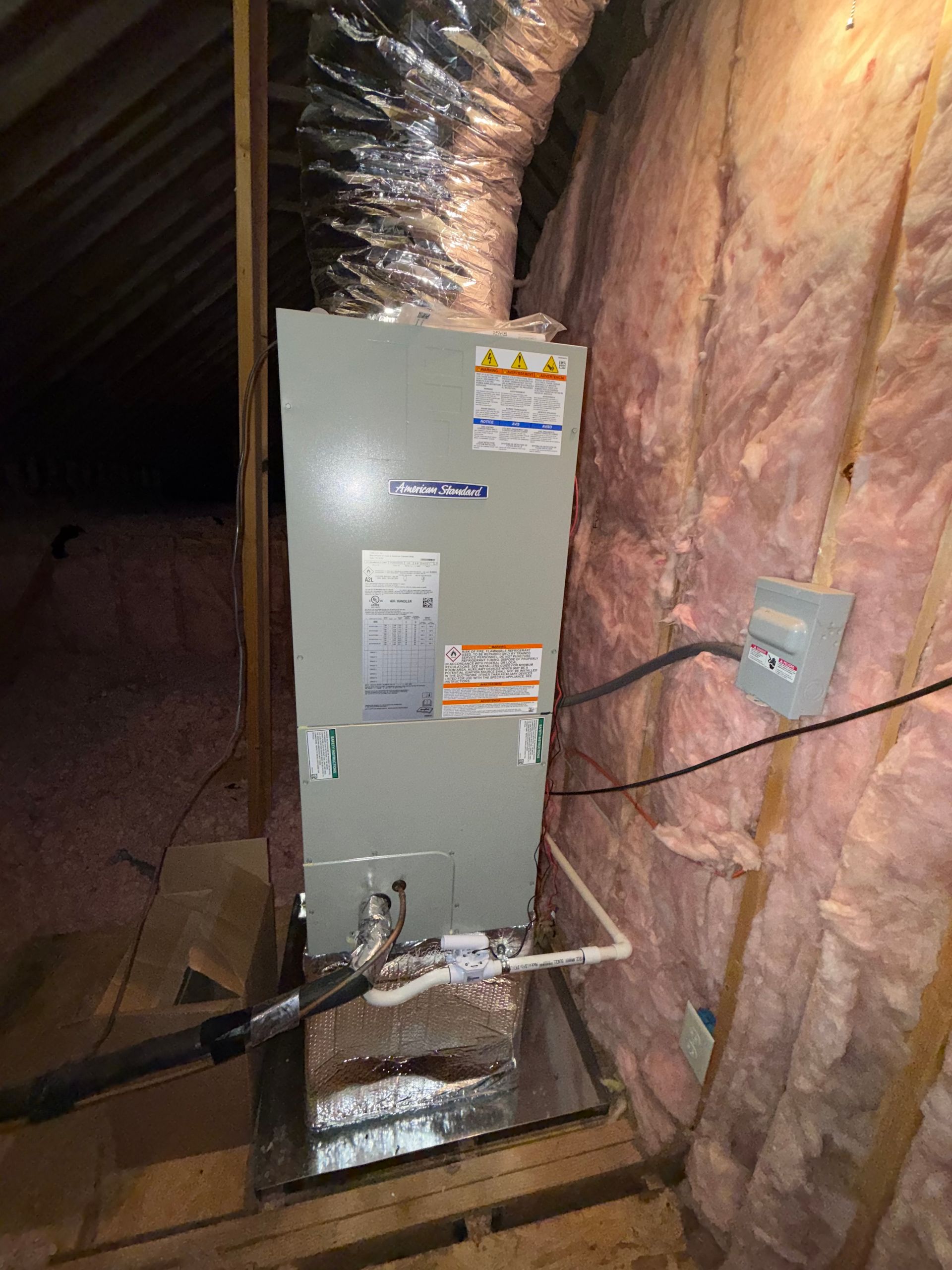 HVAC unit in an attic with insulated walls and ductwork.