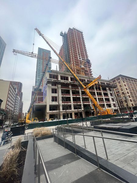 Construction site with tall buildings, cranes, and a ramp in an urban setting.