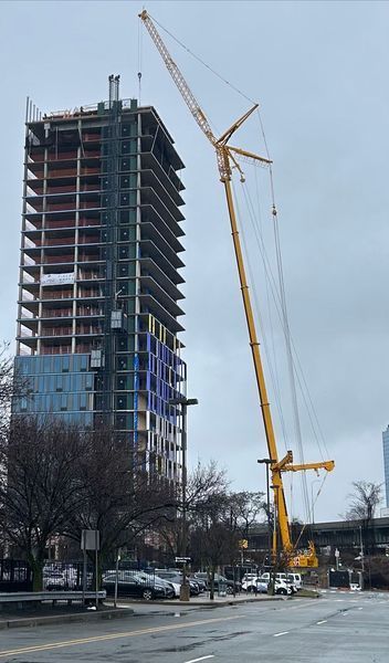 Construction crane next to a multi-story building under construction; overcast day.