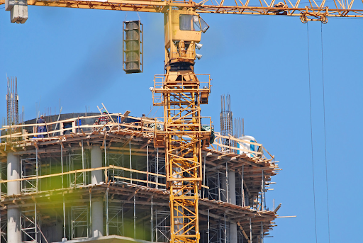 Yellow construction crane over a building under construction, blue sky background.