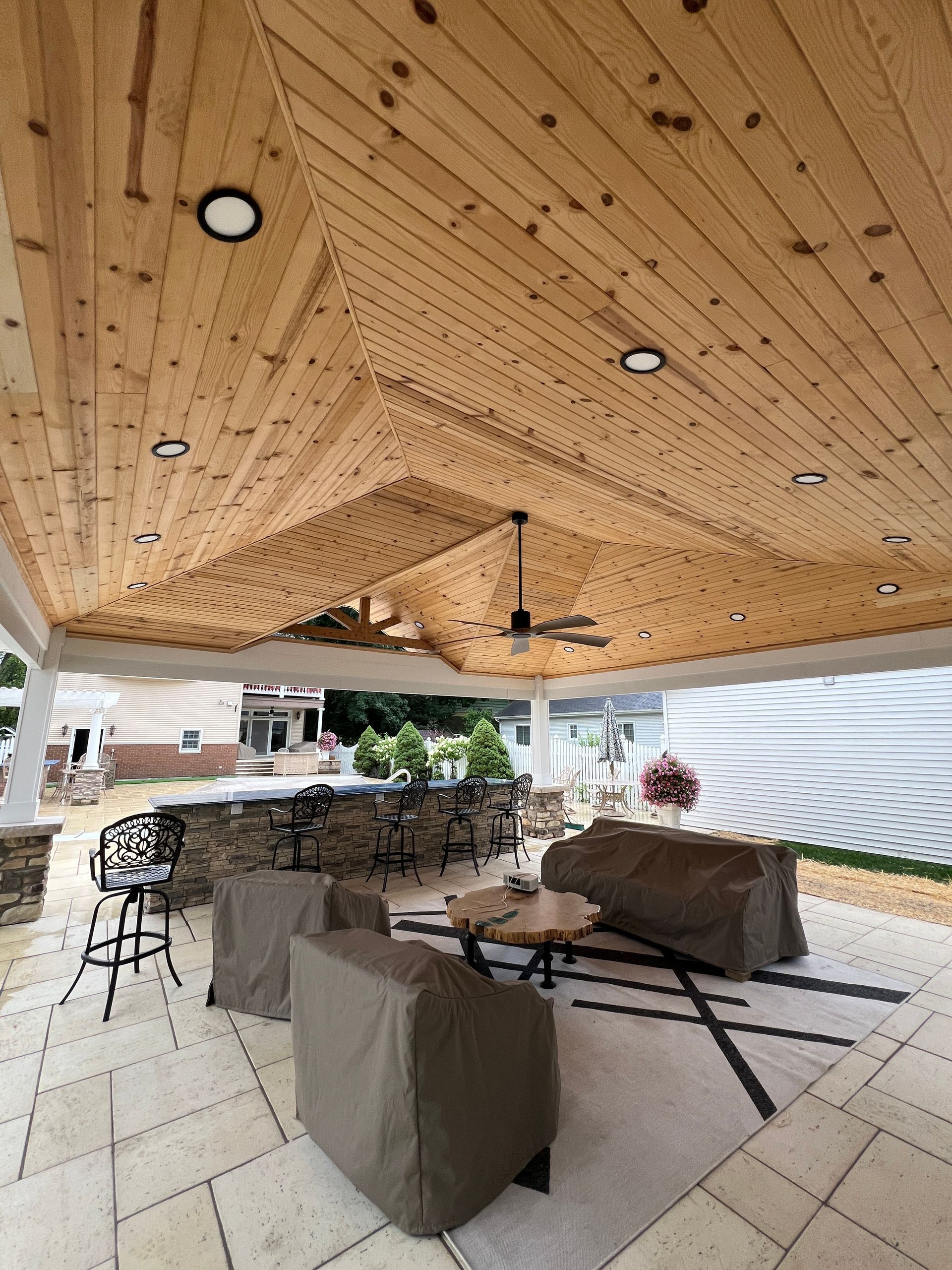 Patio with a wooden ceiling, built-in bar, and covered furniture.