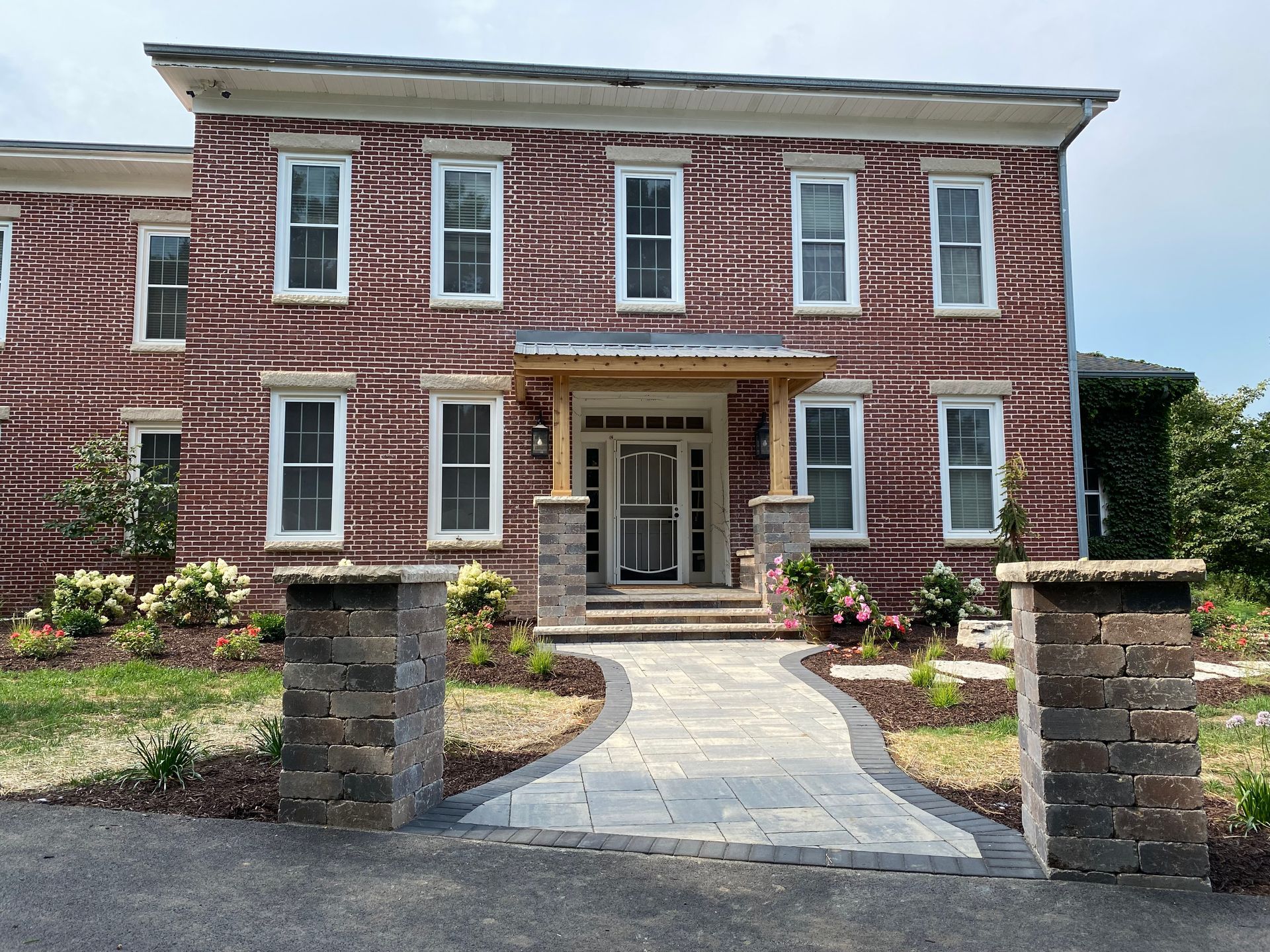 Two-story brick building with white-framed windows, a small porch, and a brick pathway leading to the front door.