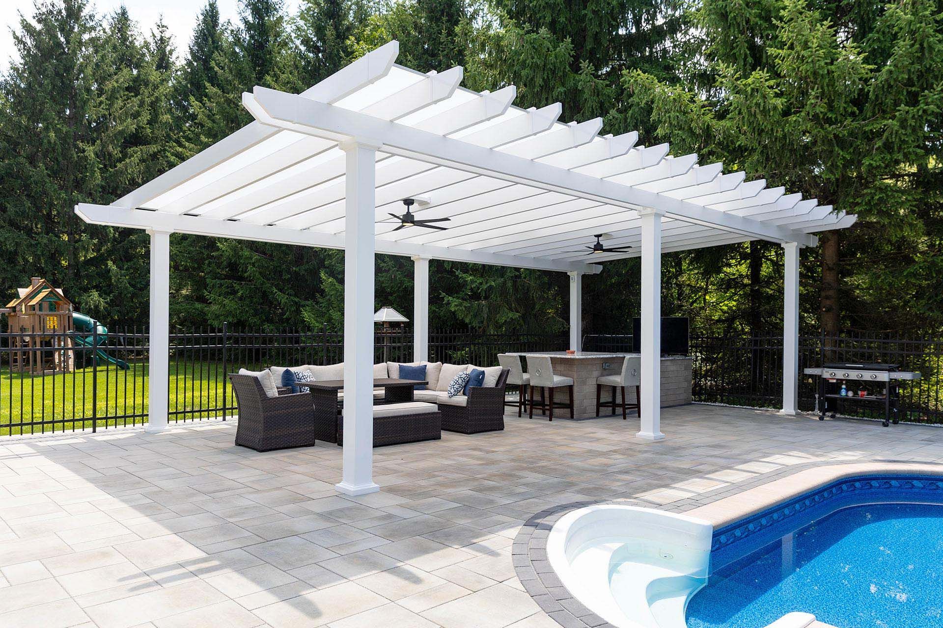 A white pergola with two ceiling fans stands over a patio