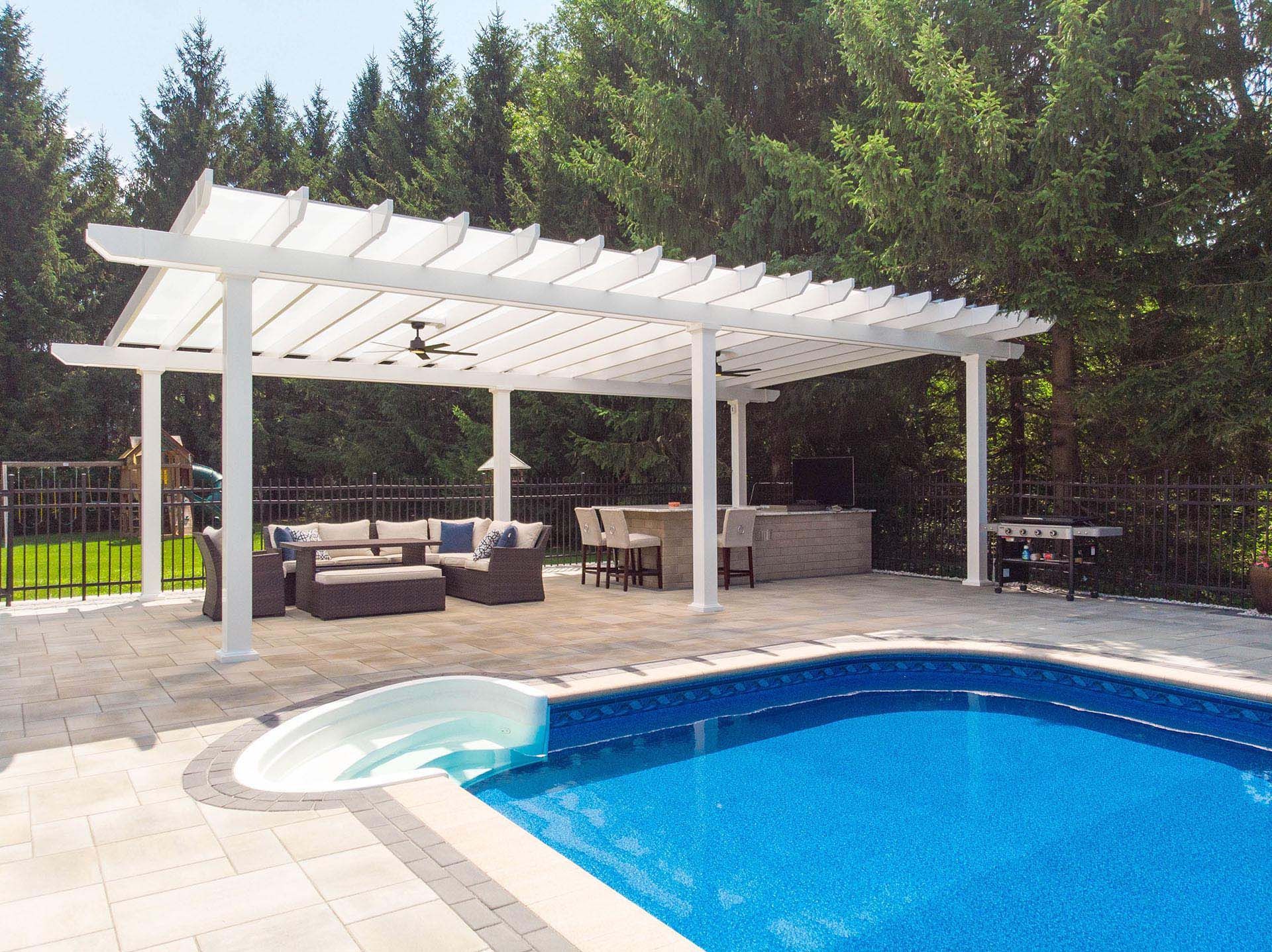 A white pergola stands on a paved patio beside a swimming pool, featuring outdoor lounge furniture and a bar area
