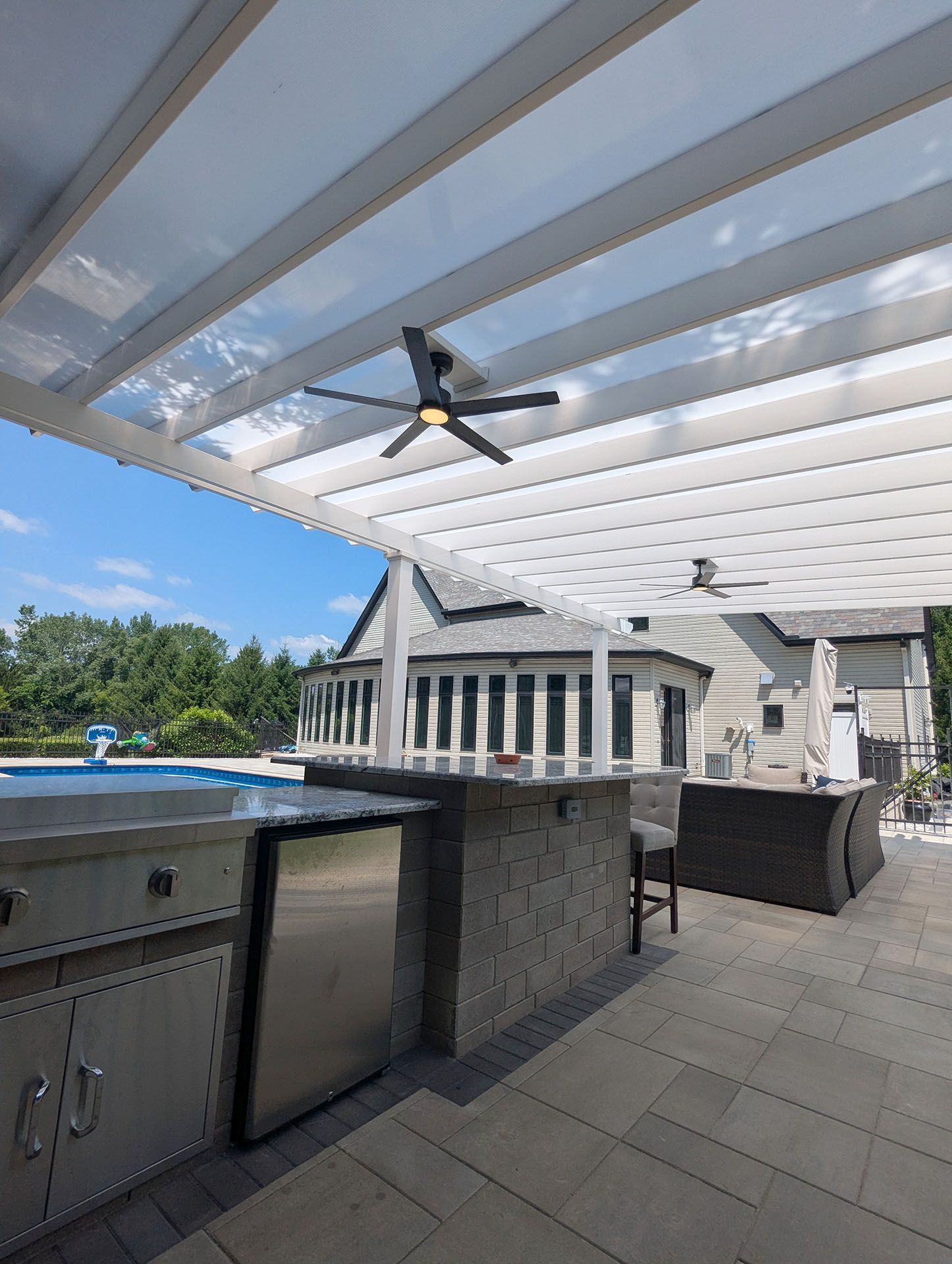 An outdoor kitchen and patio under a white pergola
