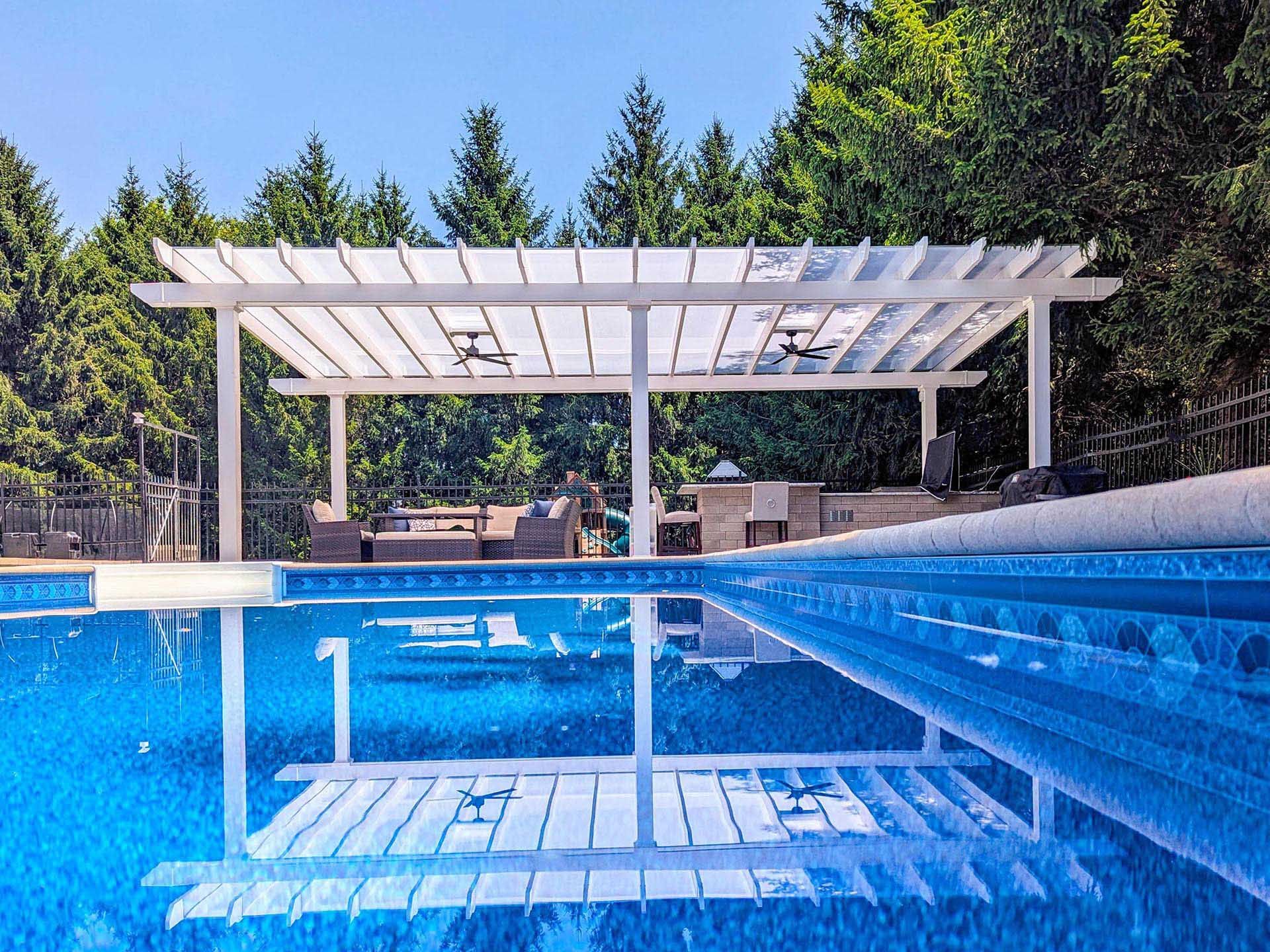 A white pergola stands by a blue swimming pool