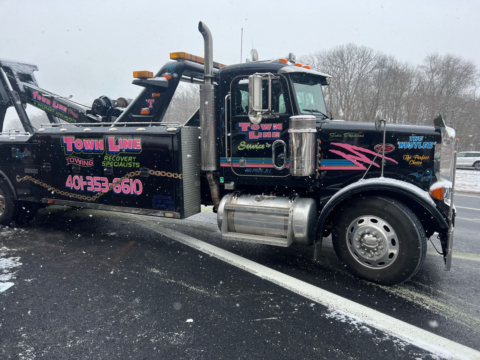 A tow truck is parked on the side of the road in the snow.