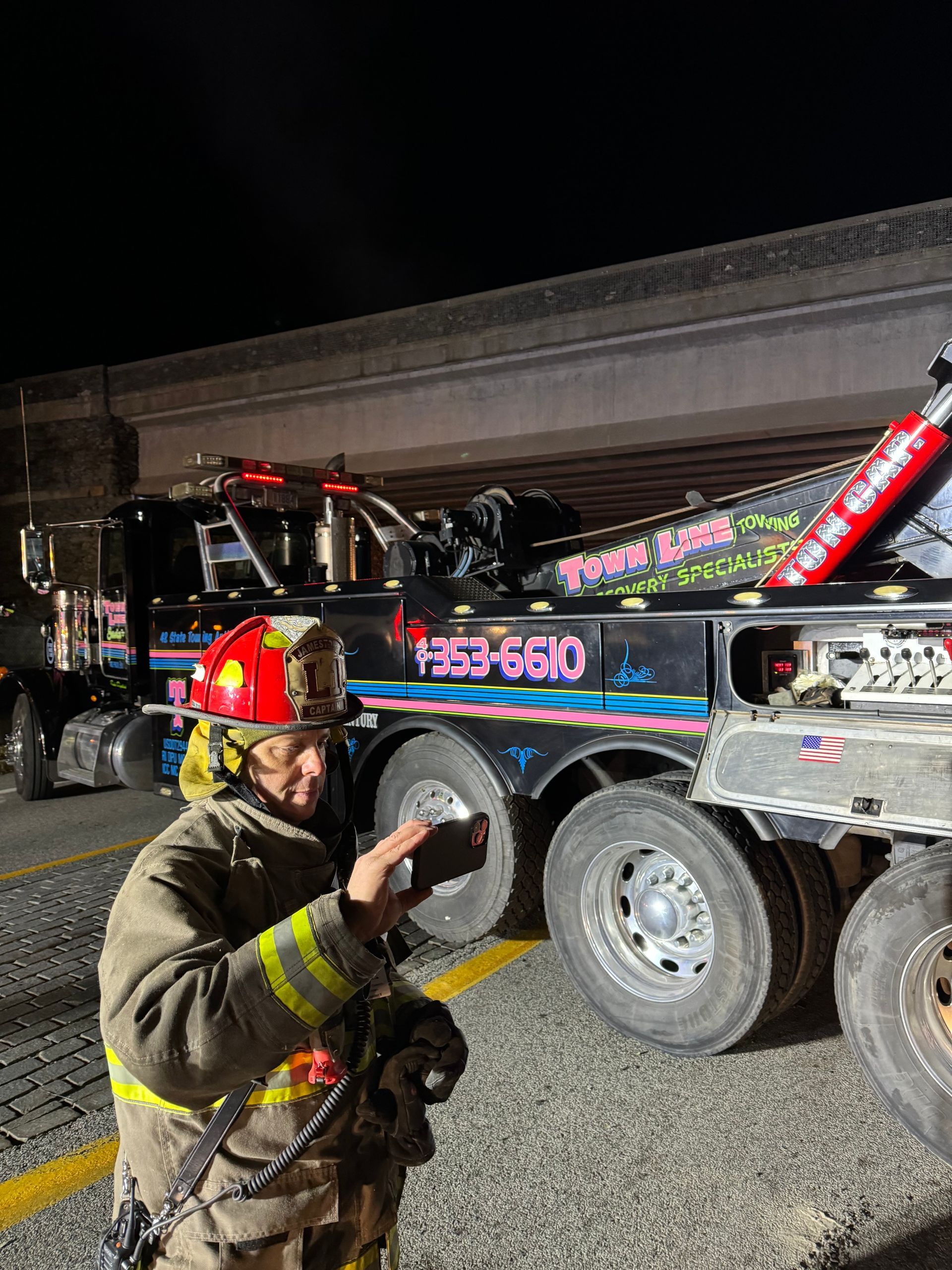A firefighter is standing next to a tow truck.