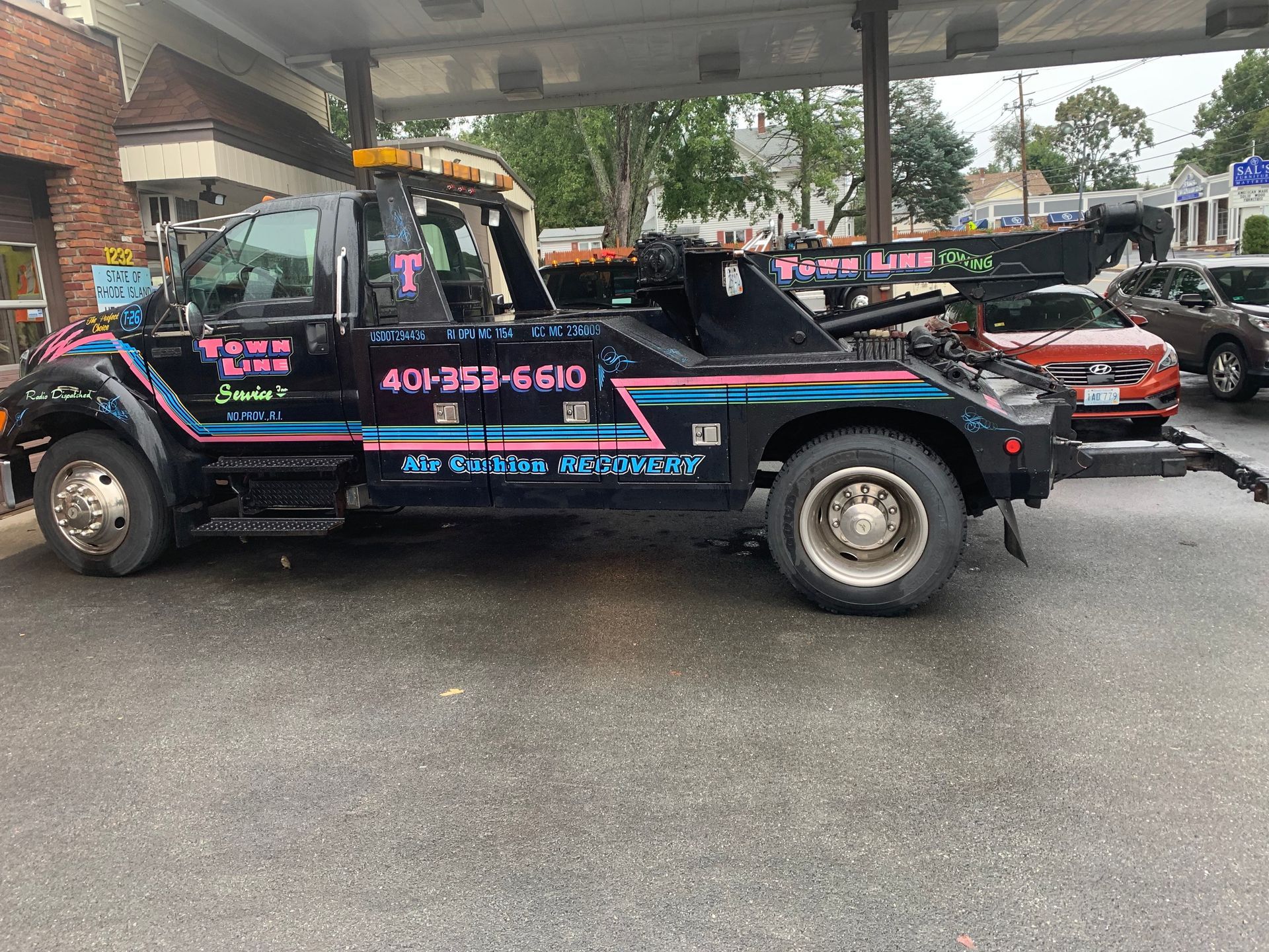 A tow truck is parked in front of a gas station.