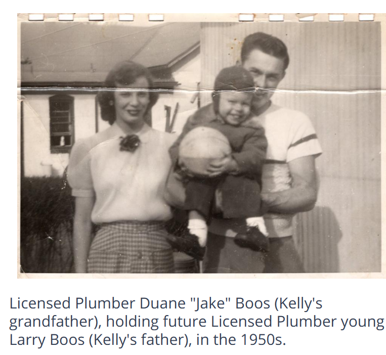Three people standing outdoors, one holding a child, in front of a house
