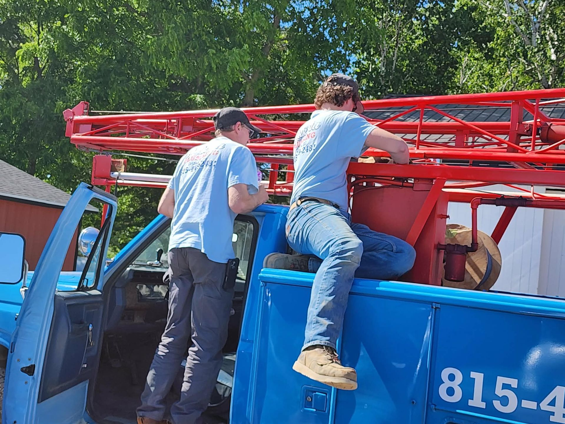 Workers loading red metal truss onto a blue truck at a construction site