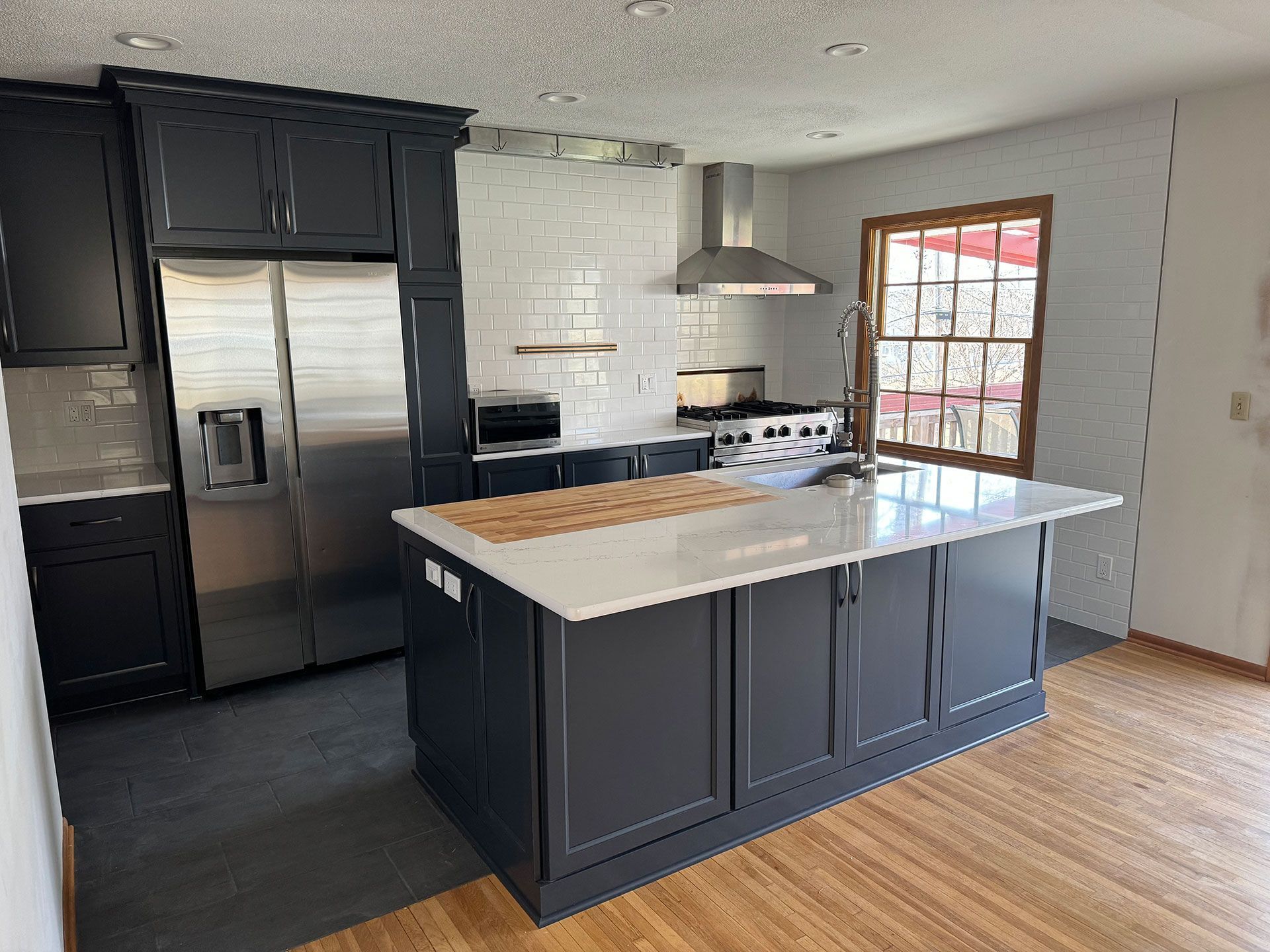 A kitchen with black cabinets and stainless steel appliances and a large island in the middle