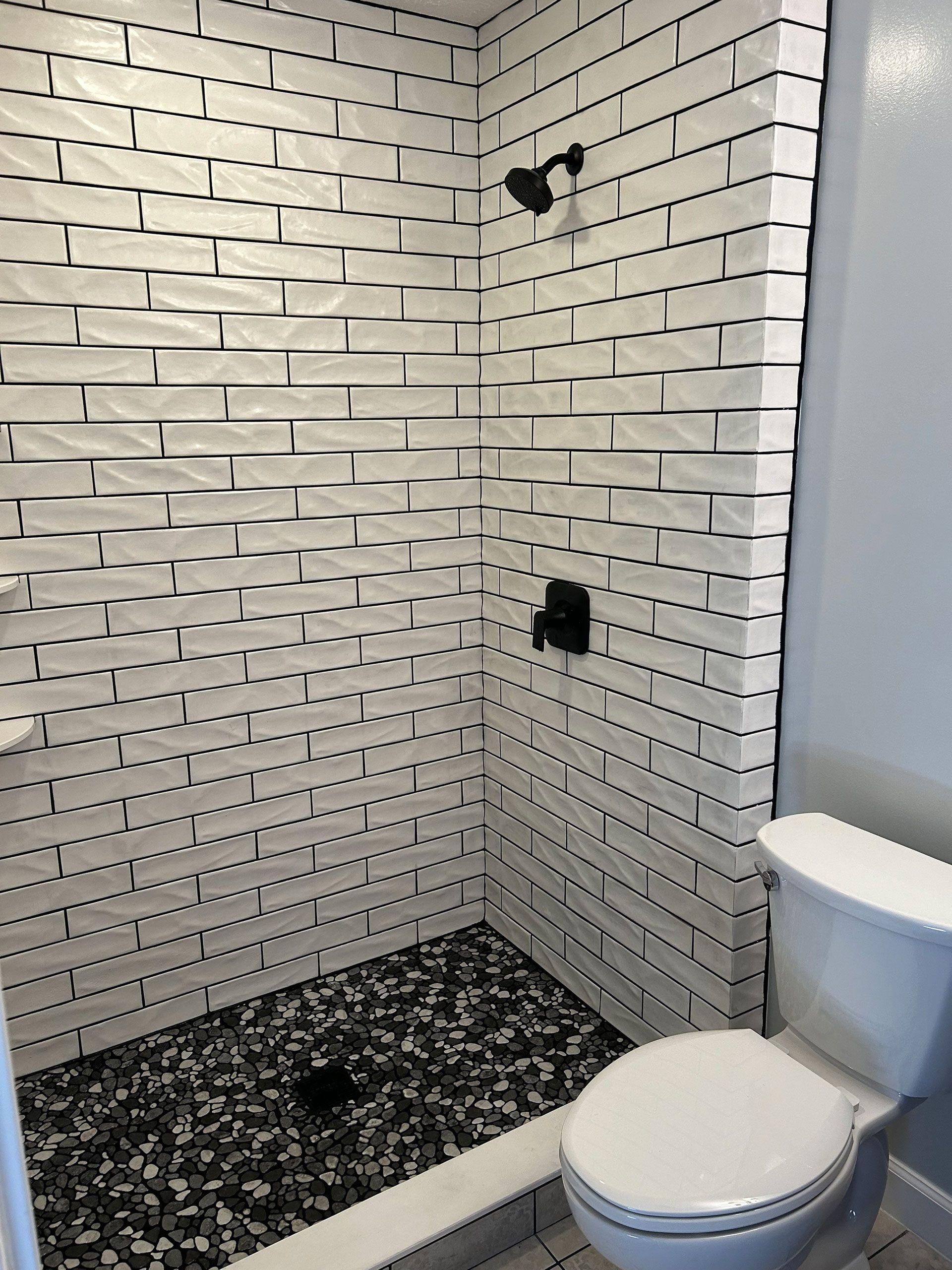 A bathroom with a toilet and a shower with black and white tiles
