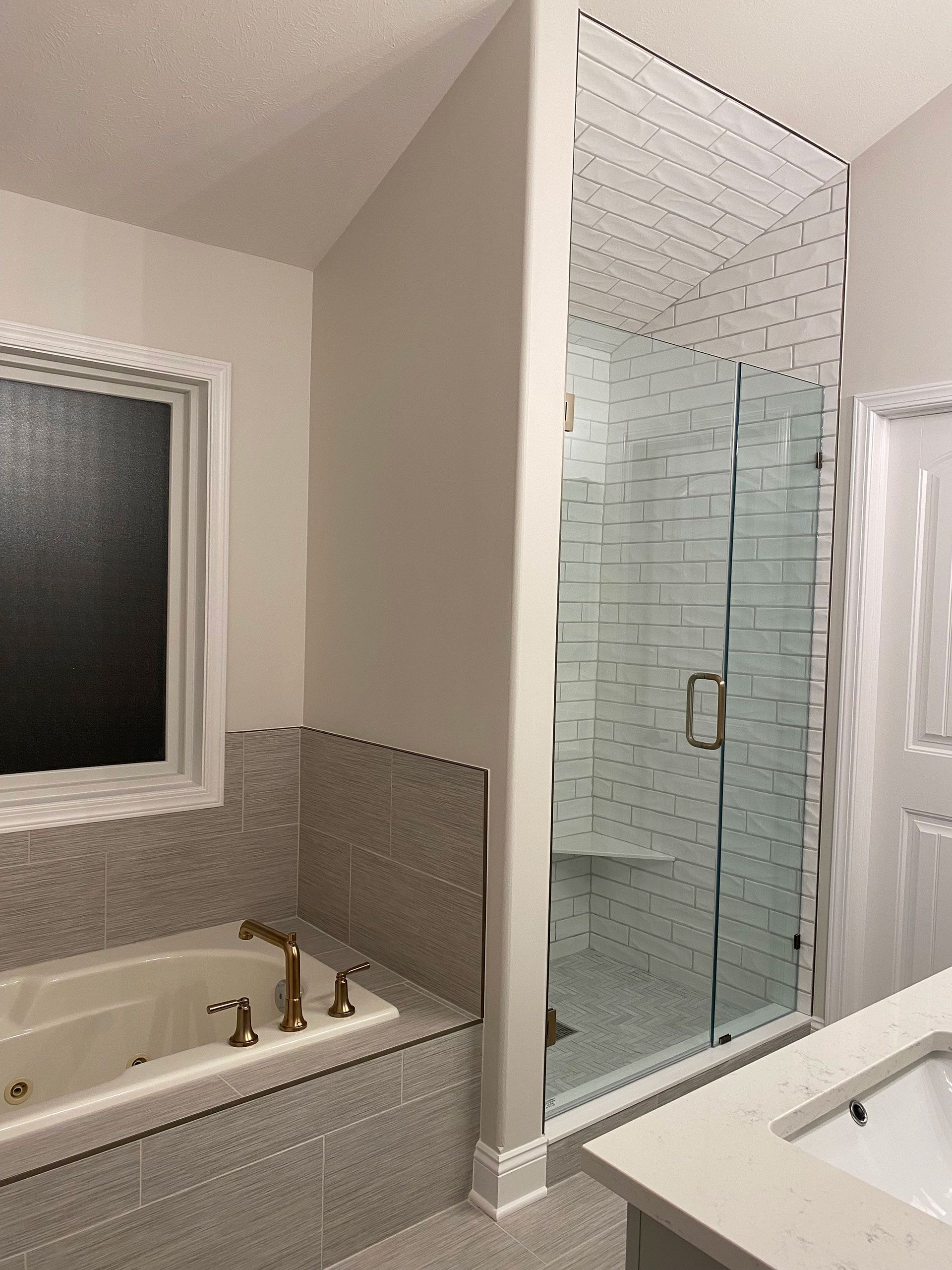 A bathroom with a tub, sink, shower and window