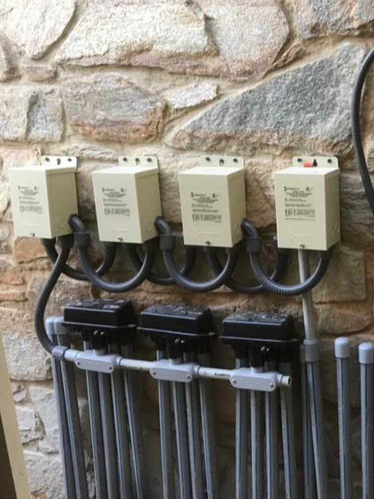 A row of electrical boxes hanging on a stone wall.