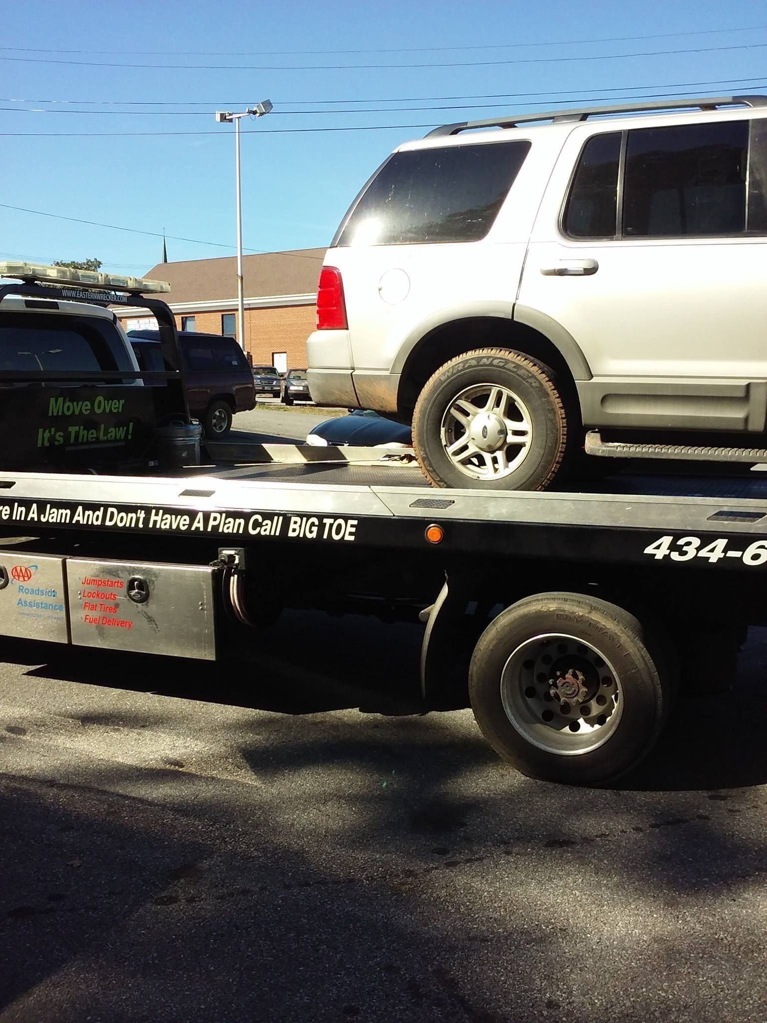SUV being towed on a flatbed tow truck on a sunny day.
