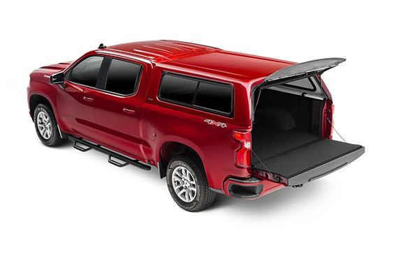 A red crew cab pickup truck with a matching canopy topper, tailgate down, parked on a white background.
