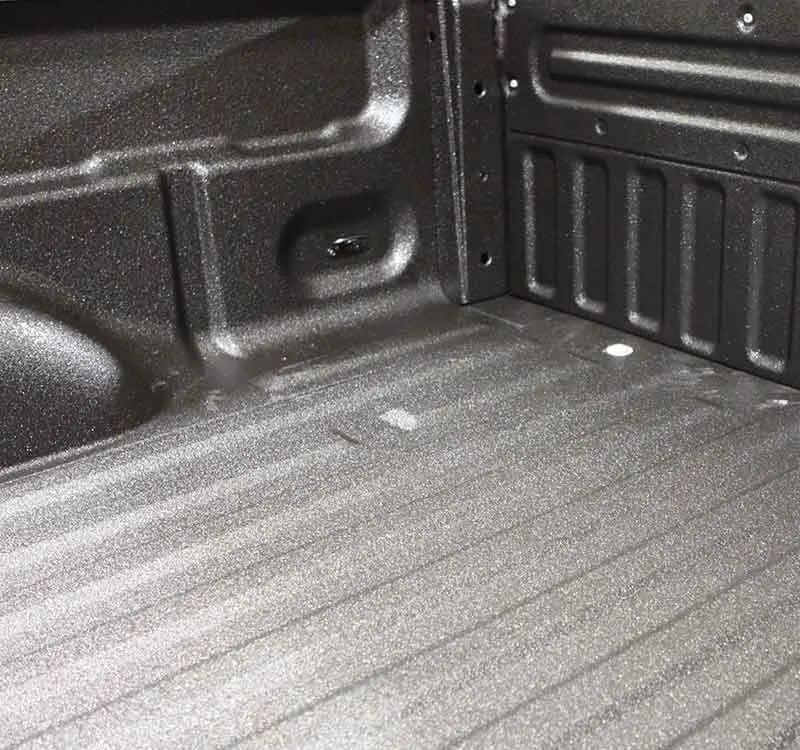 Black truck bed with textured coating. Ribbed sides and floor with tie-down points.