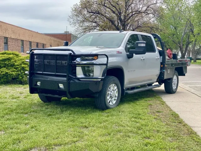 Silver work truck with a black bumper and flatbed parked on grass.
